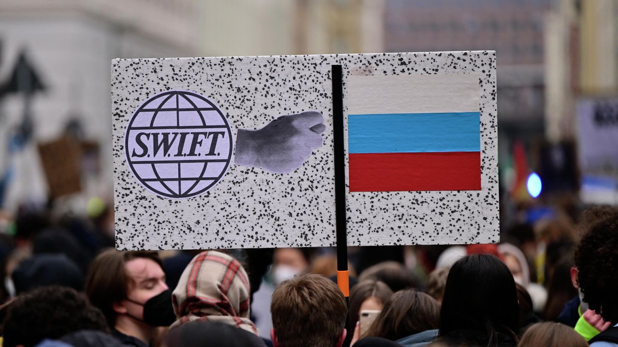 Плакат с логотипом SWIFT и флагом РФ во время демонстрации в Берлине, Германия