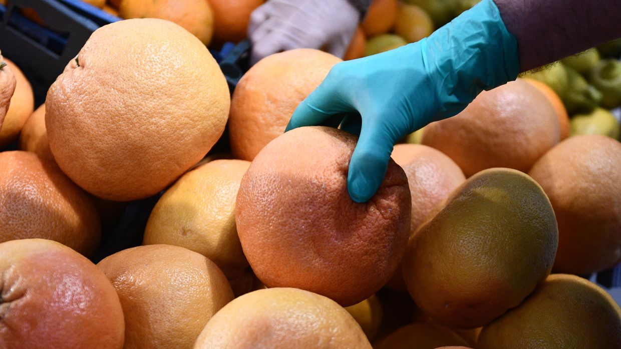 Покупатель выбирает фрукты в продуктовом магазине в Москве