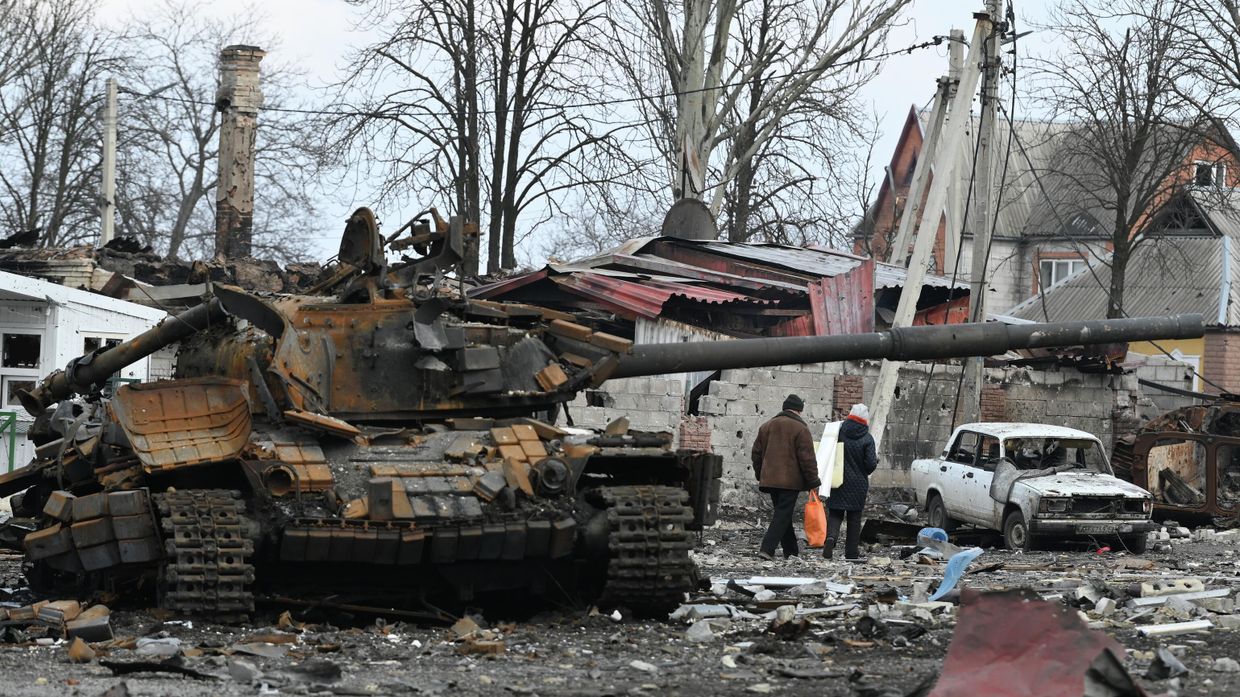 Жители Волновахи идут домой мимо разбитого танка Вооруженных сил Украины