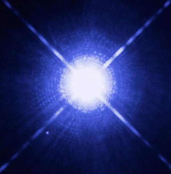 Двойная звезда Сириус A и B, более голубая и яркая, чем наше Солнце, и белый карлик, на снимках космического телескопа Хаббла. Сириус А — ярчайшая звезда на небе, но ранние оценки расстояния ошиблись, поскольку не учитывали того факта, что Сириус примерно в 20 раз ярче нашего Солнца.