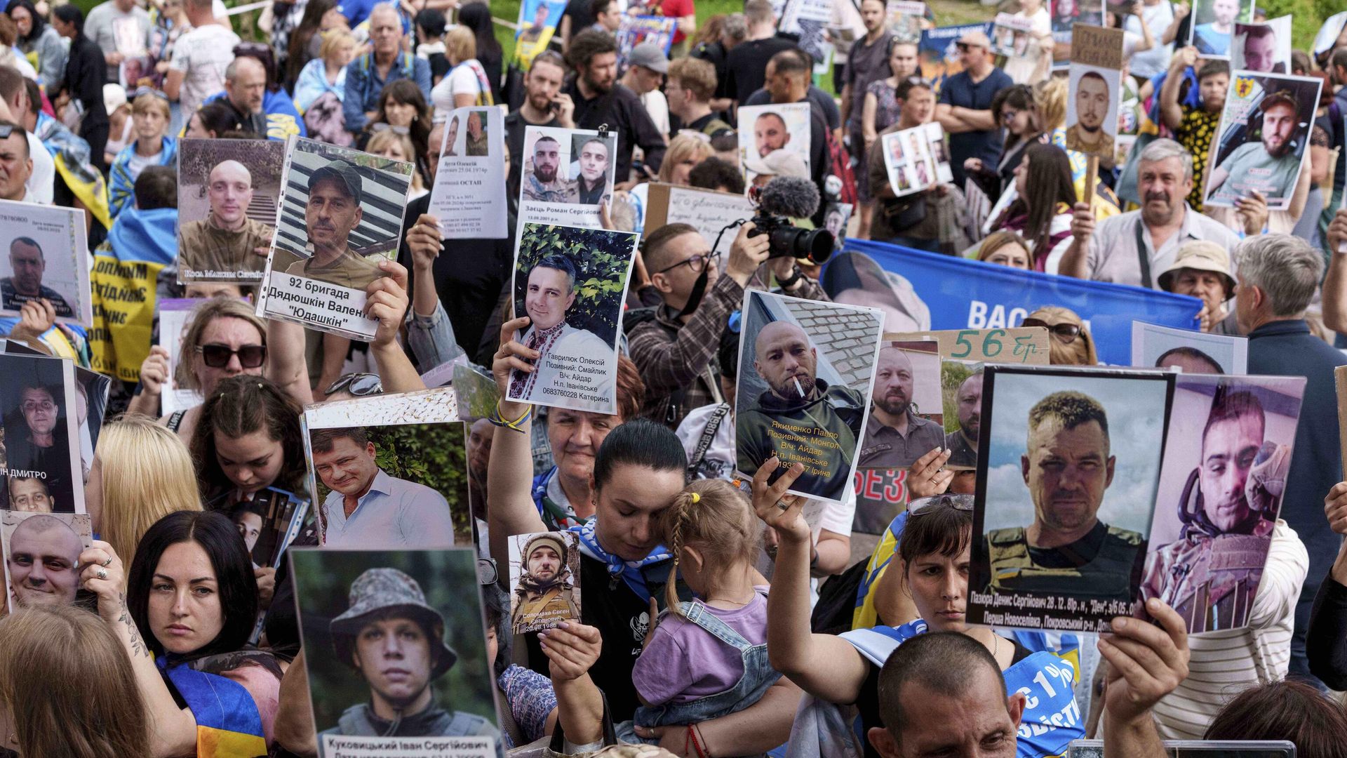 Украинцы держат в руках фотографии своих пропавших на фронте без вести родственников, встречая возвращающихся из плена солдат во время обмена между Россией и Украиной 9 июня 2025 года. - ИноСМИ, 1920, 08.08.2025