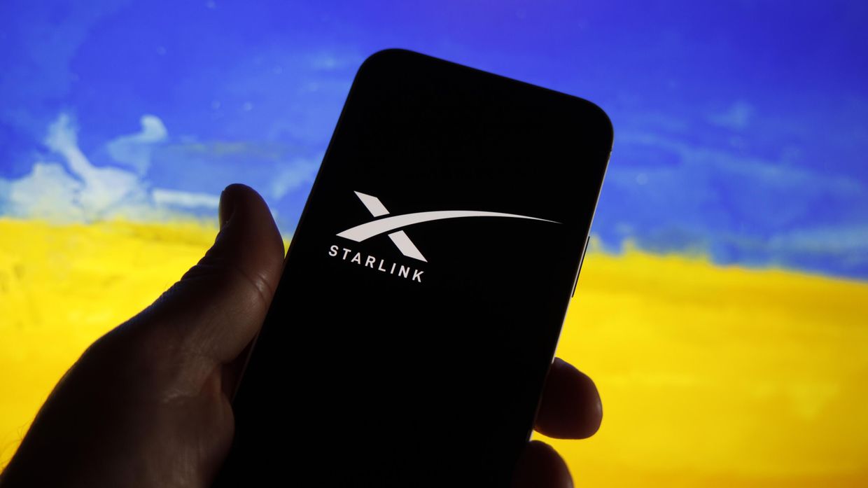 Логотип Starlink на экране смартфона на фона флага Украины