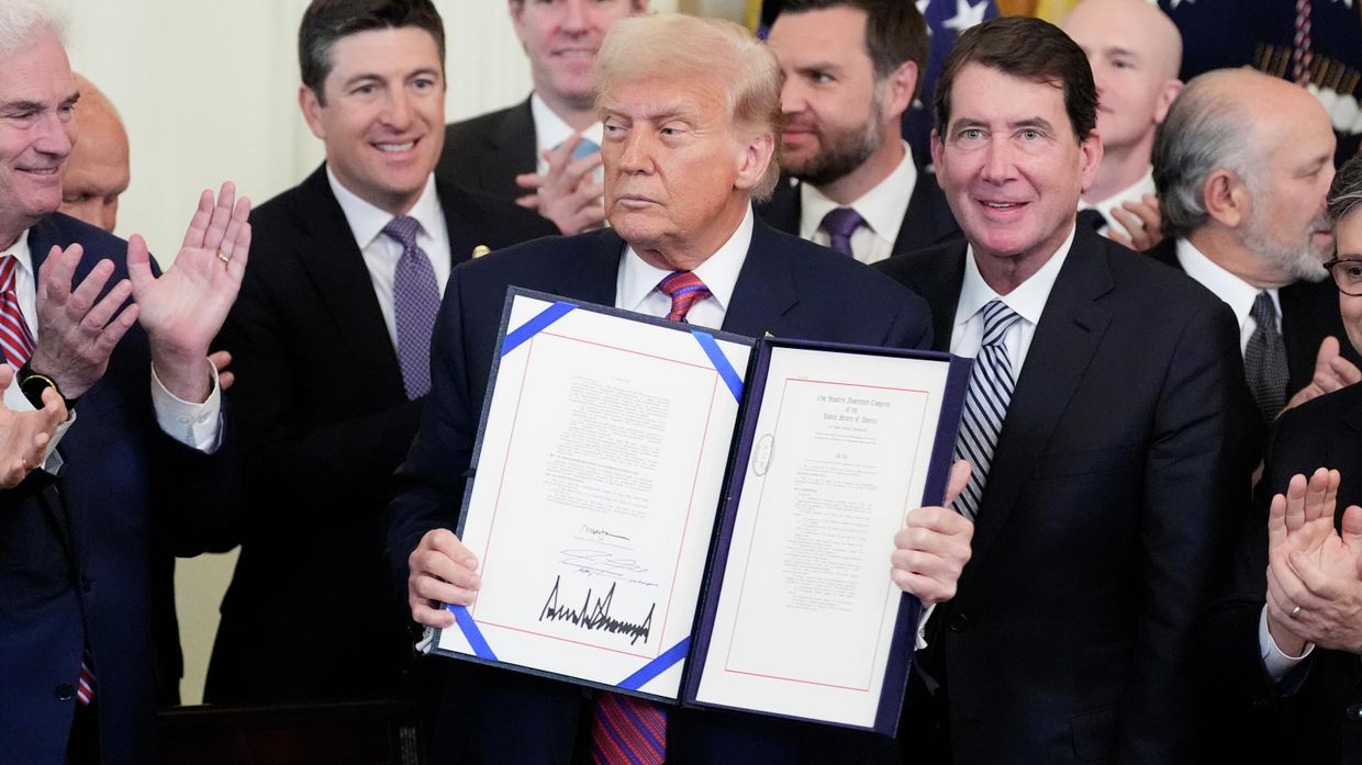 Президент Дональд Трамп держит в руках закон, регулирующий стейблкоины, разновидность криптовалюты, после того, как он подписал его в Восточном зале Белого дома 18 июля 2025 года.