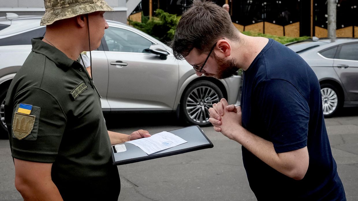 Сотрудник ТЦК раздает воинские повестки в Киеве, Украина