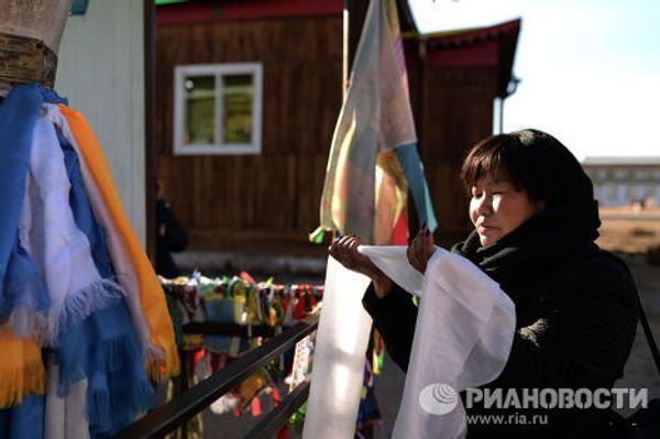 Верующая совершает обряд около одного из дуганов (храмов) при обходе Иволгинского дацана