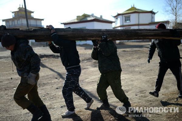 Служащие дацана несут бревно