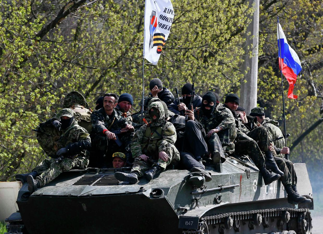 Люди, одетые в военную форму на боевой технике с флагом России в Славянске