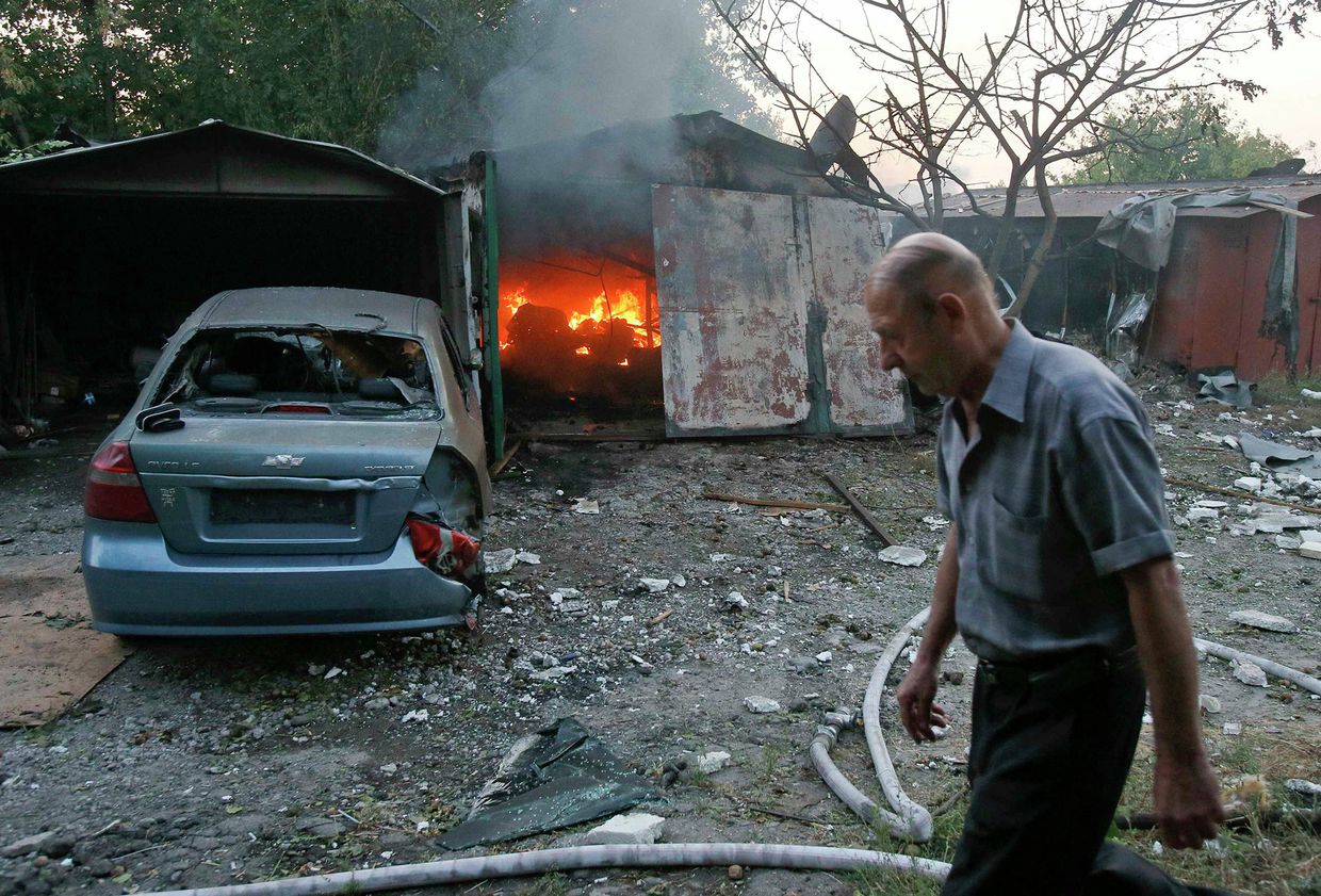 Житель у горящего в результате обстрела Украинскими военными строения в Донецке