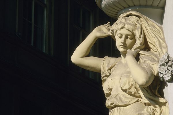 Статуя на фасаде дома на улице Тухлаубен в центре Вены