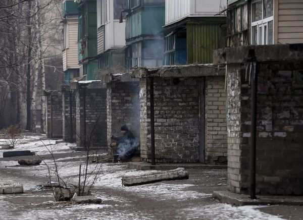 Житель Дебальцево готовит еду рядом со своим домом