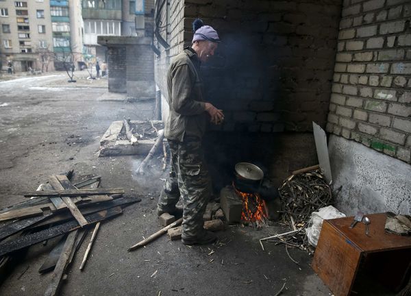 Мужчина готовит еду рядом со своим домом в Дебальцево