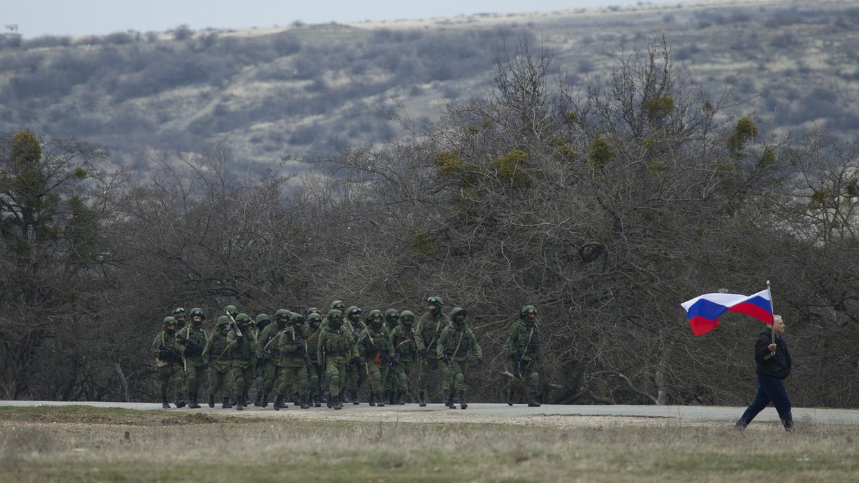 Местный житель с флагом и российские военные рядом с украинской военной базой в деревне Перевальное под Симферополем