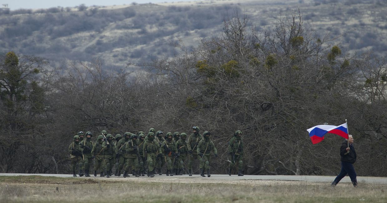 Местный житель с флагом и российские военные рядом с украинской военной базой в деревне Перевальное под Симферополем