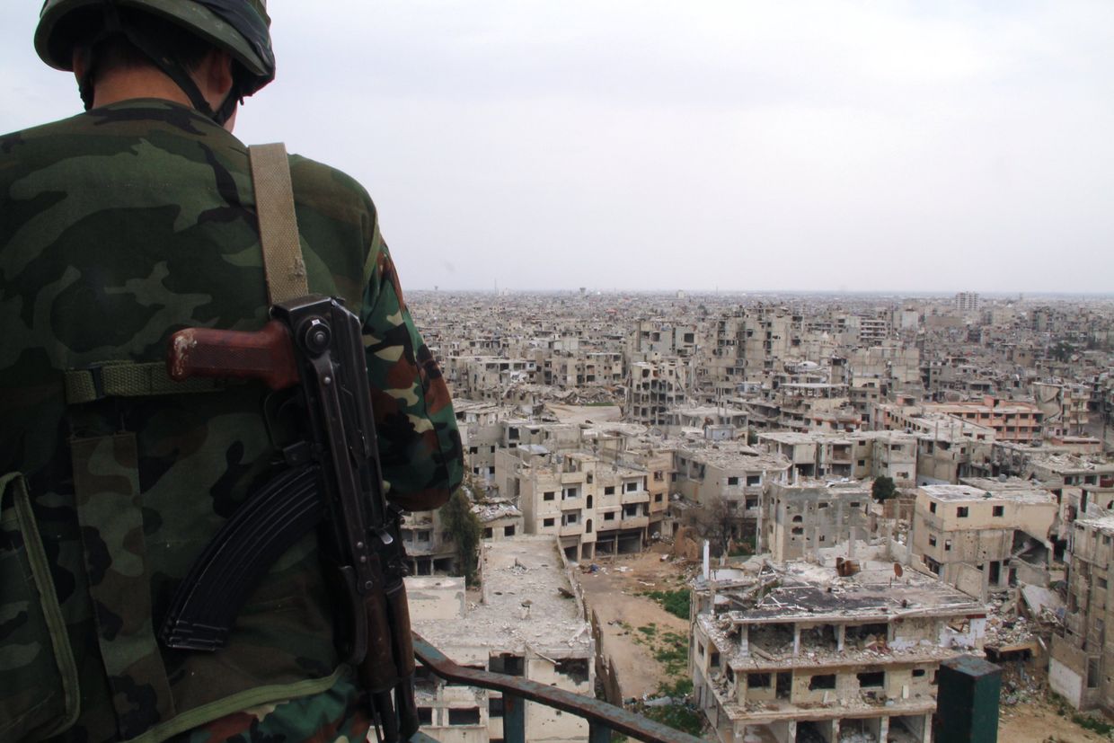 Военнослужащий сирийской армии на крыше одного из зданий, разрушенных в результате боевых действий, в Хомсе