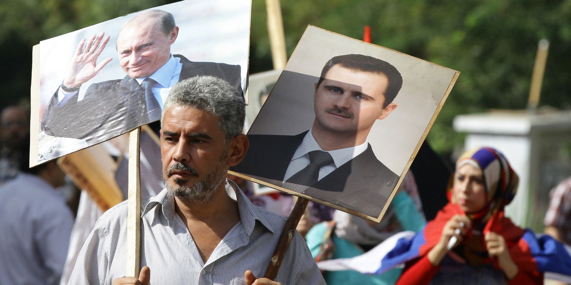 Сириец держит плакаты с изображениями Владимира Путина и Башара Асада на акции в поддержку российских военных действий в Сирии, Дамаск - ИноСМИ, 1920, 09.03.2023