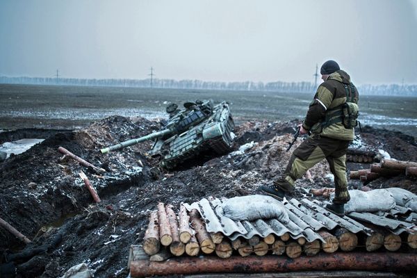 Ополченец стоит у танка украинской армии в Донецкой области Ополченец стоит у танка украинской армии в Донецкой области