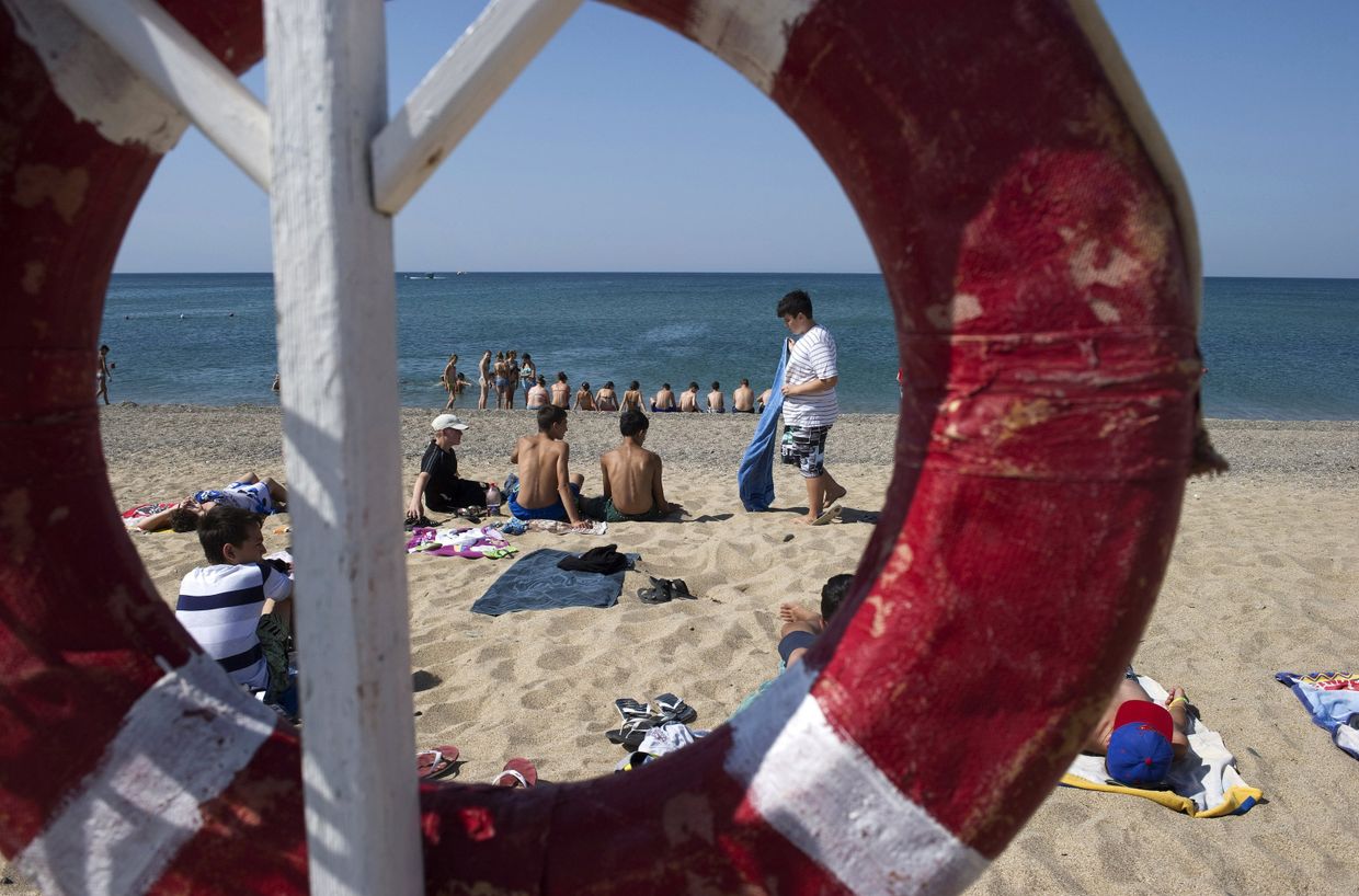 Отдыхающие на пляже Черного моря у детского оздоровительного лагеря «Голубая волна»
