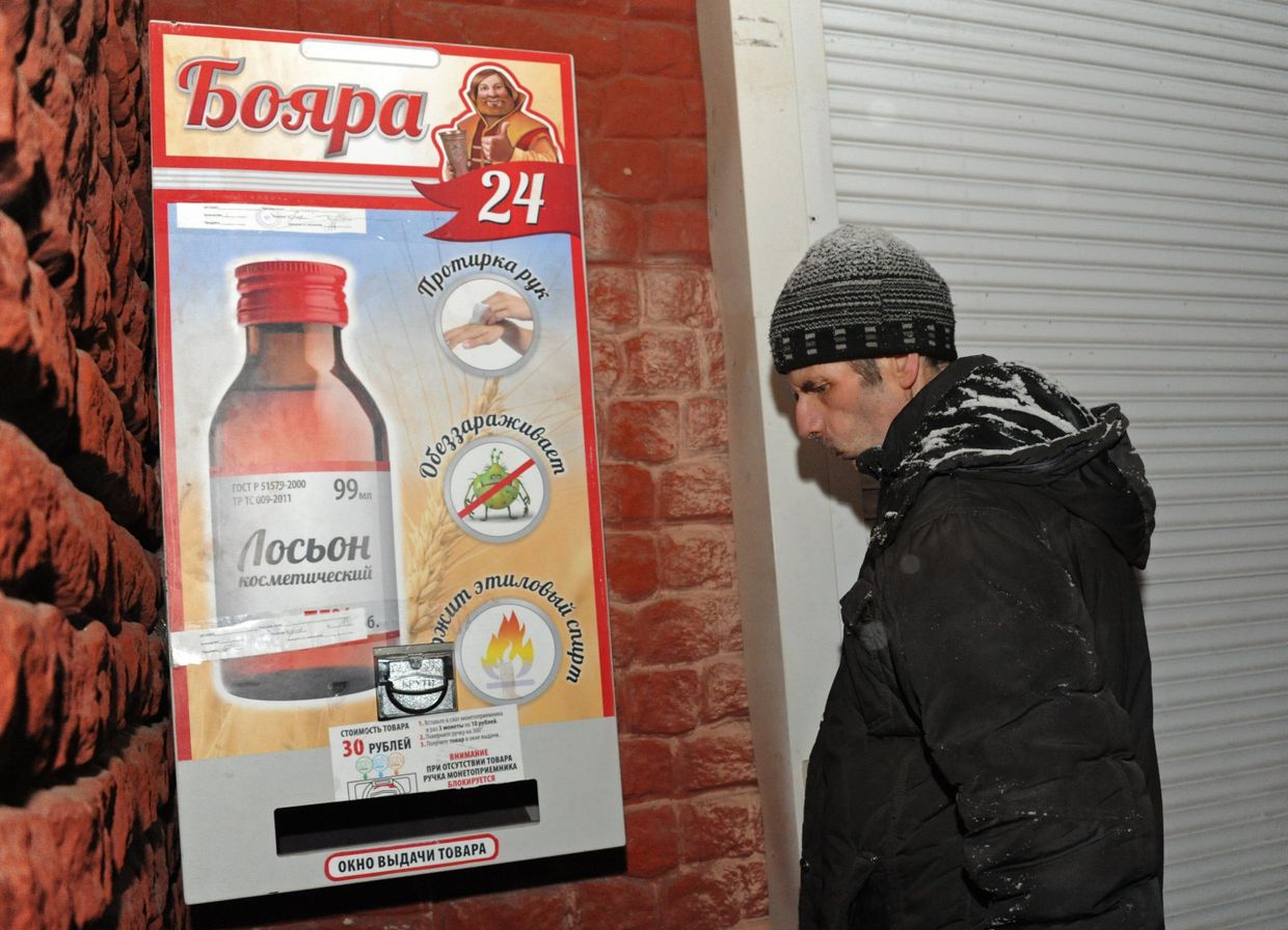 Мужчина у автомата по продаже спиртосодержащего средства с боярышником