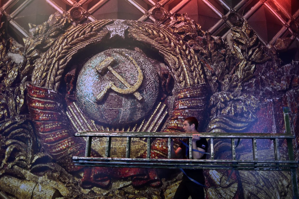 Рабочий с лестницей на фоне изображения герба СССР