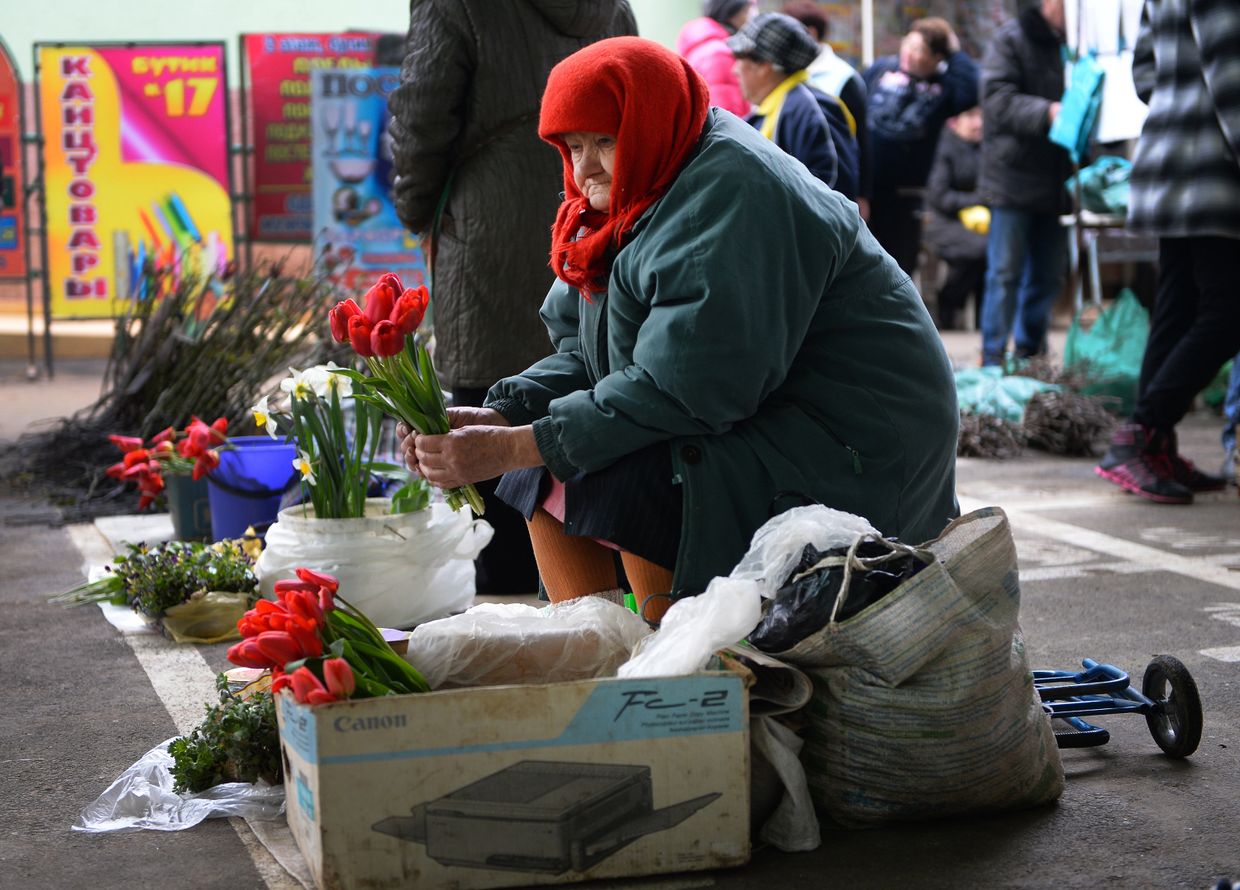 Пожилая женщина продает цветы на местном рынке в Тирасполе