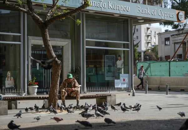 Мужчина кормит голубей у закрытого офиса Bank of Cyprus в Никосии