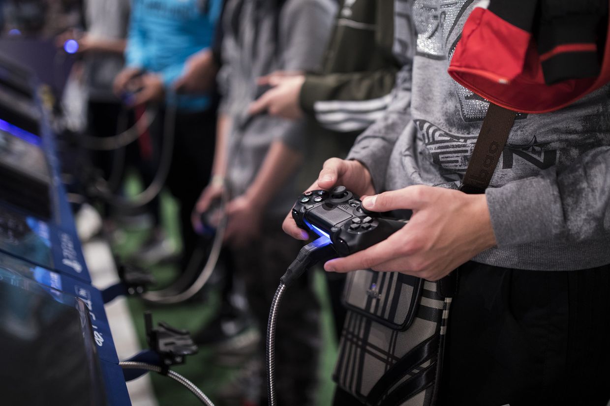 Геймеры играют в приставку Playstation 4 на Paris Games Week в Париже