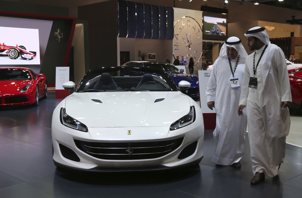 Посетители перед автомобилем Ferrari Portofino на Dubai Motor Show в ОАЭ. 14 ноября 2017