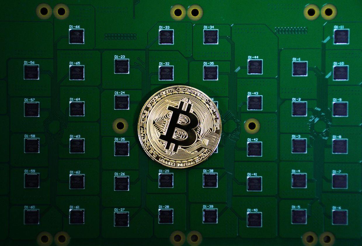 Сувенирная монета биткоина на фоне электрических плат