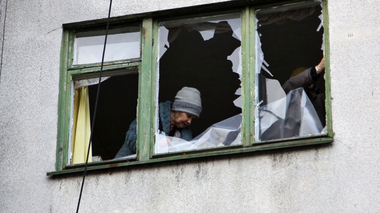 Женщина у окна жилого дома в центре города Ясиноватая, пострадавшего в результате обстрела