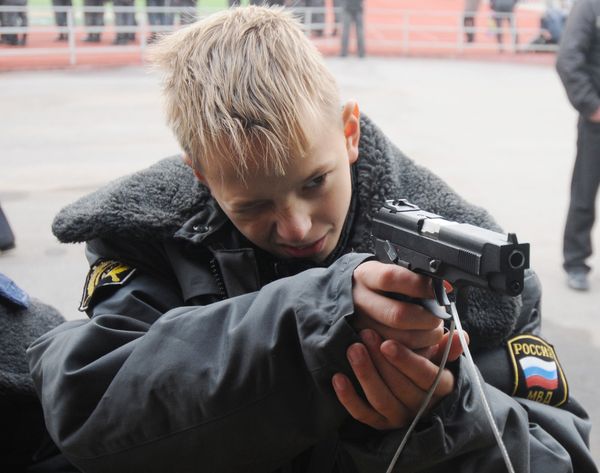 Ребенок целится из пистолета Ярыгина во время спортивного праздника