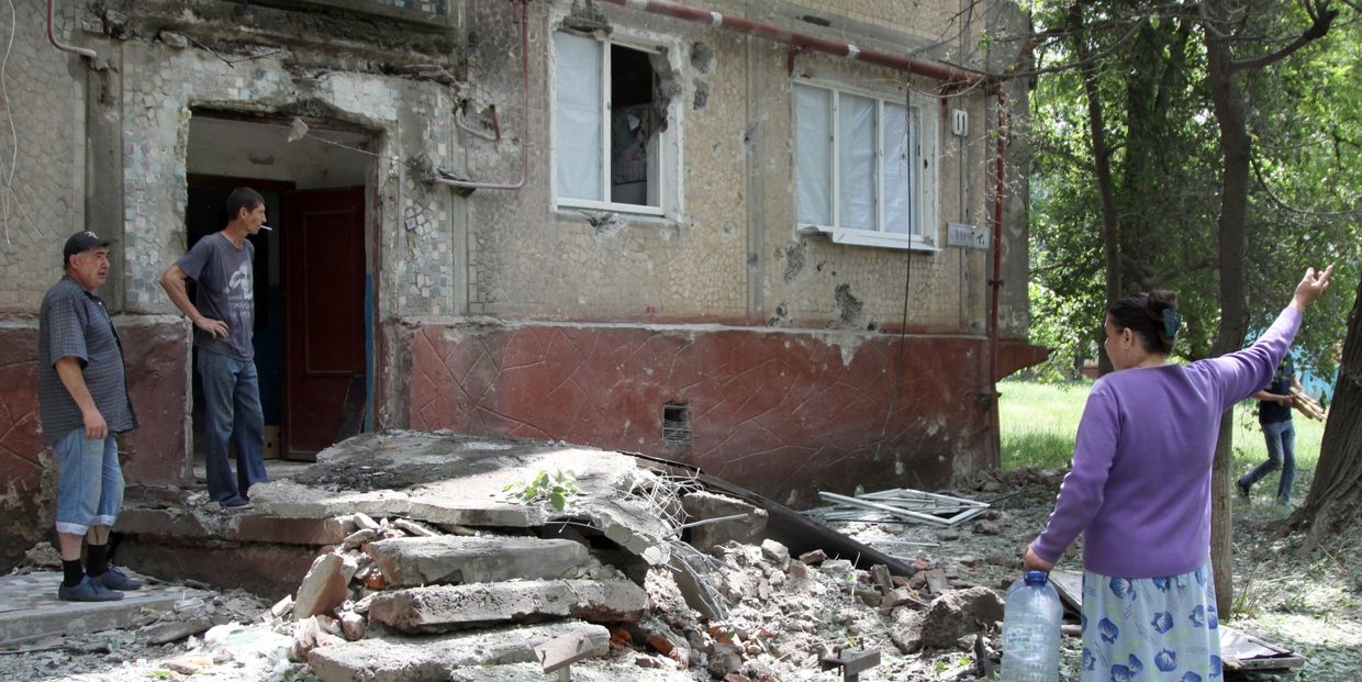 Жители во дворе жилого дома, пострадавшего в результате обстрела, в поселке Горловка Донецкой области