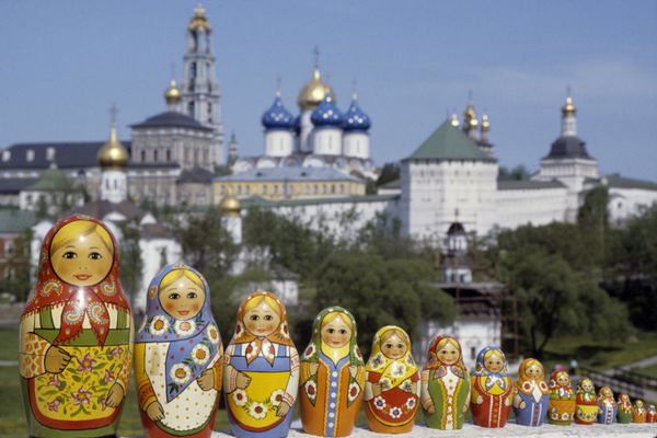Русские матрешки, сфотографированные на фоне Троице-Сергиевой лавры