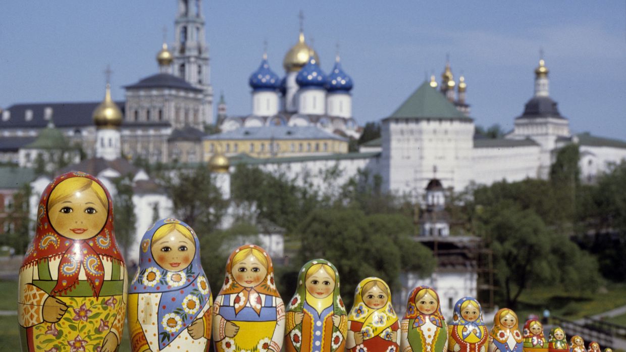 Русские матрешки, сфотографированные на фоне Троице-Сергиевой лавры