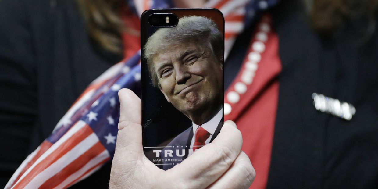 Женщина держит телефон с фотографией Дональда Трампа во время предвыборной кампании в США