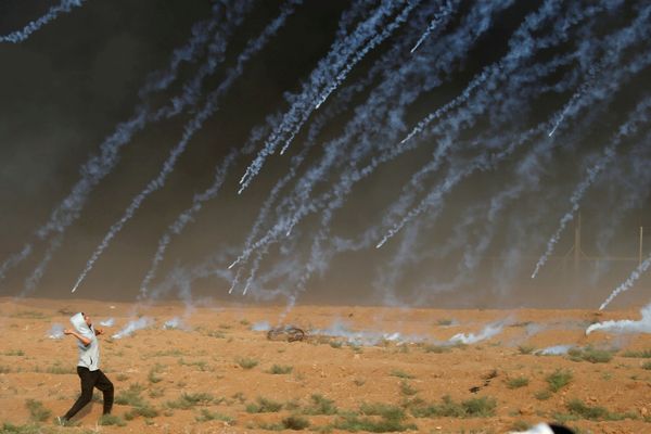 Палестинский демонстрант бросает камни в израильские войска во время акции протеста у пограничного ограждения между Израилем и сектором Газой