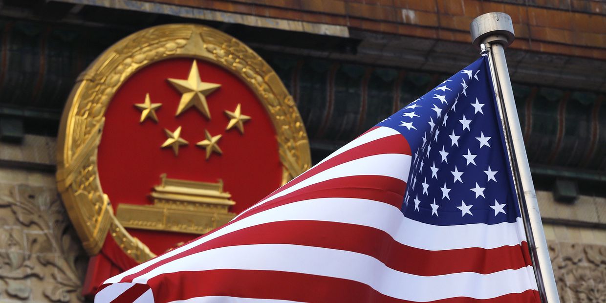 Флаг США на фоне эмблемы Китая в Пекине