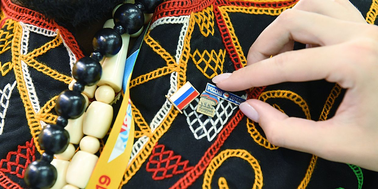Участнику экономического форума Россия - Африка прикрепляют значок МИА Россия сегодня.