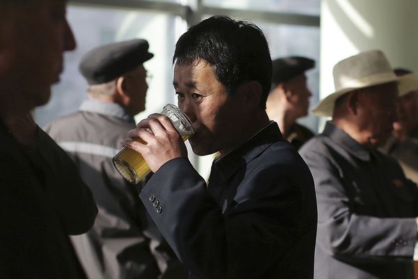 Мужчина пьет пиво в Пхеньяне, КНДР