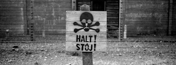 Деревянный знак «Стоп» у забора с колючей проволокой в Освенциме