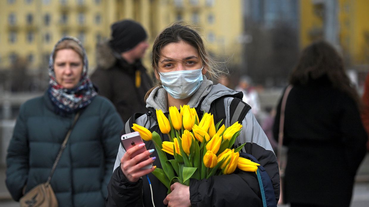Девушка с цветами и в маске на Пушкинской набережной в Парке Горького в Международный женский день в Москве
