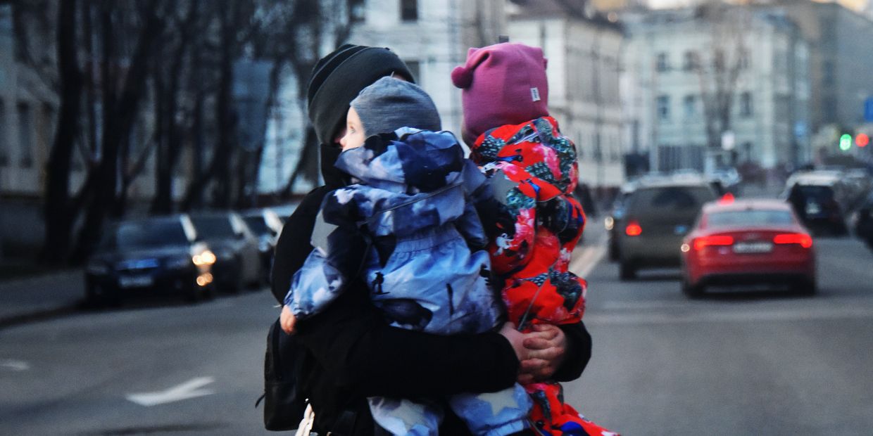 Женщина с двумя детьми на руках переходит дорогу Женщина с двумя детьми на руках переходит дорогу