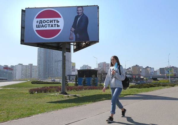 Девушка у рекламного щита, установленного в Киеве в связи с коронавирусом. Надпись: «Хватит шастать»