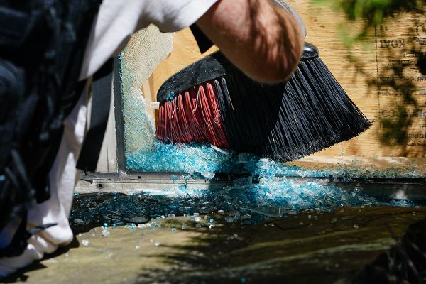 Мужчина убирает осколки стекла в пострадавшем от беспорядков магазине в Атланте