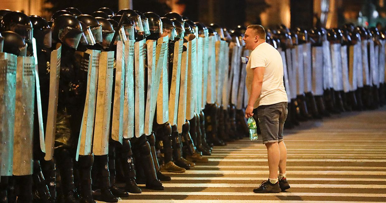 Протестующий говорит с полицией во время митинга в Минске