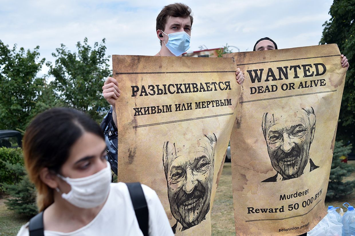 Люди с плакатами, изображающими президента Белоруссии Александра Лукашенко во время акции протеста в Минске