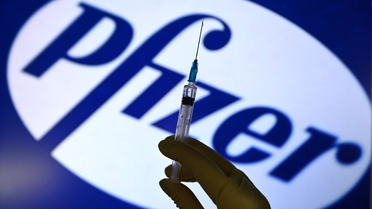 Шприц на фоне логотипа Pfizer