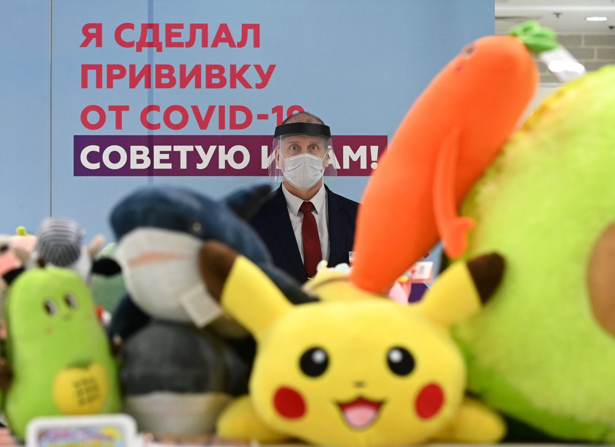 Сотрудник торгового центра «Европейский» возле агитплаката у пункта вакцинации от коронавируса Сотрудник торгового центра «Европейский» возле агитплаката у пункта вакцинации от коронавируса