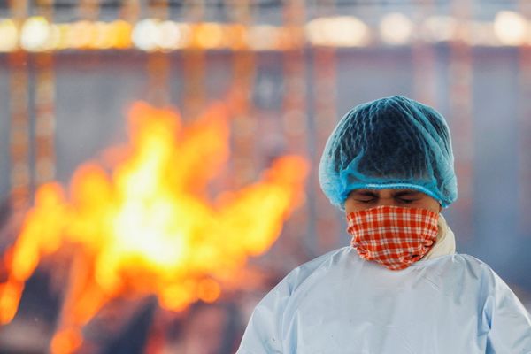 Мальчик скорбит по умершему от коронавируса отцу, чье тело горит в крематории в Нью-Дели, Индия