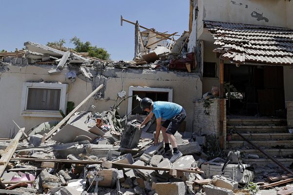 Израильтянин Элиша Голан разбирает завалы в своем доме в городе Йехуд